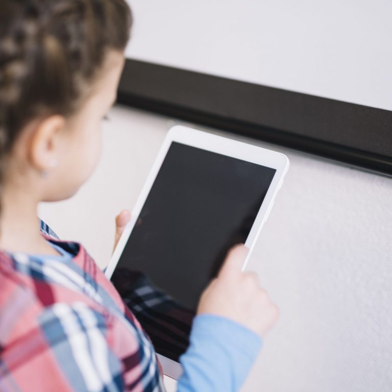 little girl holding a tablet or an ipad and staring at it